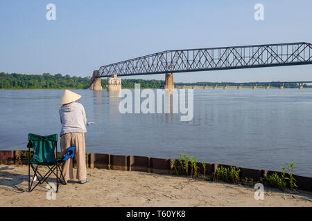 Persone asta di pesca sul fiume Mississippi con la vecchia catena di rocce ponte in background Foto Stock