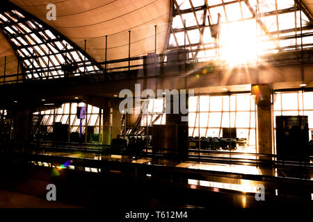 Silhouette di interno di Suvarnabhumi Airport (VTBS) terminale passeggeri in una giornata di sole con sunburst attraverso il tetto di vetro Foto Stock