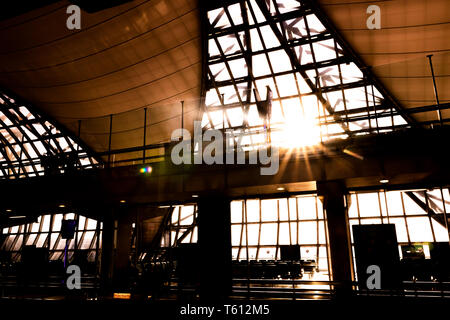 Silhouette di interno di Suvarnabhumi Airport (VTBS) terminale passeggeri in una giornata di sole con sunburst attraverso il tetto di vetro Foto Stock