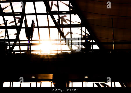 Silhouette di interno di Suvarnabhumi Airport (VTBS) terminale passeggeri in una giornata di sole con sunburst attraverso il tetto di vetro Foto Stock