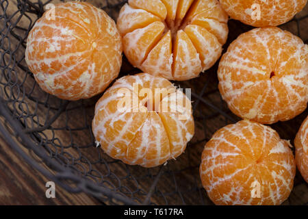 Sbucciate fresche Clementine nel vecchio cestello di metallo Foto Stock