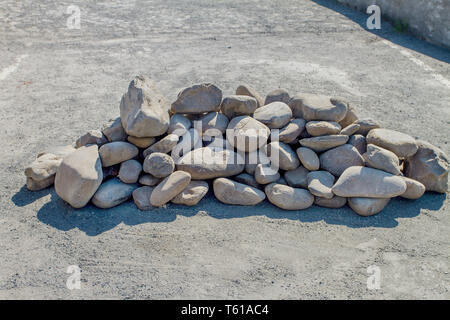 Pila di pietre arrotondate accatastati nel mezzo della strada Foto Stock