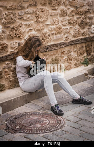 Young Teen girl frugando nello zaino seduti sui gradini della vecchia casa Foto Stock