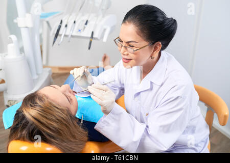 Dentista esaminando denti del paziente femmina Foto Stock