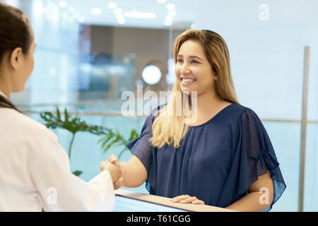 Sorridente paziente femmina agitando la mano su doctor Foto Stock