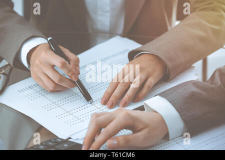 Due femmina commercialisti contando sulla calcolatrice entrate fiscali per formare il completamento mani di close-up. Business e concetto di audit Foto Stock