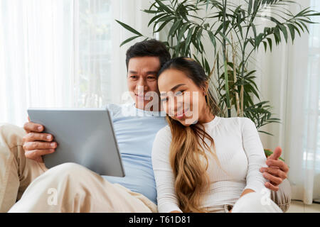 Coppia sorridente appoggiato con il computer tablet Foto Stock