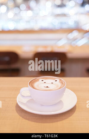 Carino sostenere latte caffè caldo in tazza bianca sulla tavola di legno, leggere per servire. Foto Stock