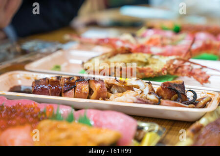 Calamari alla griglia e altri sushi; salmone, otoro, anguilla, Grigliata di gamberi, granchi sono disposti sul tavolo pronti a mangiare. Foto Stock