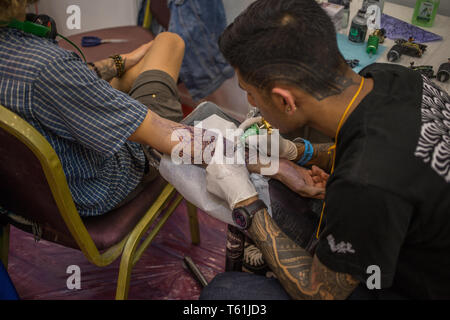 Un uomo come ottenere un tatuaggio al tatuaggio annuale convention di Kathmandu, Nepal Foto Stock