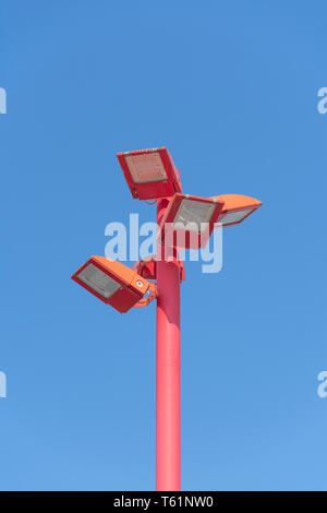 Close up di un led rosso palo di illuminazione con quattro lampade ed un cielo blu come sfondo verticale Foto Stock