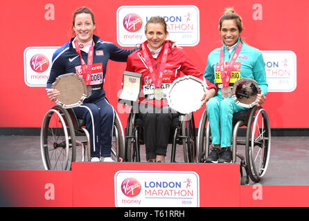 Svizzera di Manuela Schar (centro) celebra con il trofeo dopo aver vinto la donna della Maratona di sedia a rotelle accanto al secondo posto negli Stati Uniti che Tatyana McFadden (sinistra) e il terzo posto in Australia il Madison de Rozario (a destra) durante il 2019 denaro Virgin London Marathon. Foto Stock