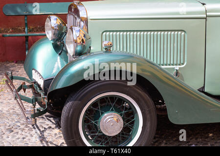 Parafango, la ruota e il faro anteriore di una annata 1932 auto parcheggiate in Fortaleza de Sao Tiago a Funchal. Verde auto, nichelato lucido, proiettore vecchio acciottolato Foto Stock