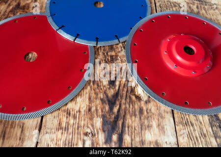 Diamante rosso ruote per granito e pietra, blu per calcestruzzo di cemento armato, su una tavola di legno vecchio sfondo della scheda Foto Stock