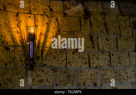 Illuminato il castello medievale di torcia appeso ad un muro di pietra, gli oggetti vintage e lo sfondo Foto Stock