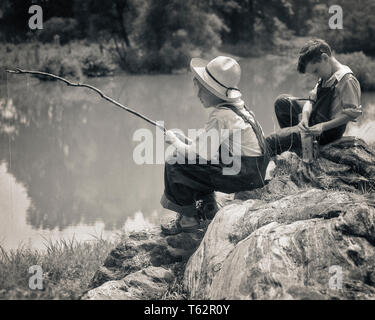 Negli anni Trenta due ragazzi seduti sulle rocce la Pesca nel laghetto con pali da ramoscelli e STRING - un5121 HAR001 HARS LEISURE E VISTA POSTERIORE I gemelli realizzati cappello di paglia Huck Finn bastoni ramoscelli ANGLING BIB tuta Tom Sawyer VISTA POSTERIORE Huckleberry Finn novellame pre-teen pre-teen BOY RELAX convivere in bianco e nero di etnia caucasica HAR001 in vecchio stile Foto Stock