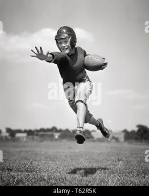 1940s ragazzo che indossa il casco di calcio in esecuzione uniforme che porta la sfera entrambi i piedi da terra la carica MIDAIR - b11528 HAR001 HARS FISICO ISPIRAZIONE FITNESS ATHLETIC FIDUCIA B&W la libertà di attività gli obiettivi di felicità FORZA FISICA emozione basso angolo QUARTERBACK RICREAZIONE DIREZIONE ORGOGLIO OPPORTUNITÀ ATLETI DI CARICA FLESSIBILITÀ MIDAIR MUSCOLI HALFBACK palloni da calcio pre-teen pre-teen BOY football americano in bianco e nero di etnia caucasica HAR001 in vecchio stile Foto Stock