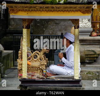 Leader di preghiera in una piccola cabina, Pura Tirta Empul temple, Ubud, Indonesia Foto Stock