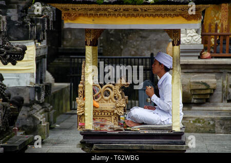 Leader di preghiera in una piccola cabina, Pura Tirta Empul temple, Ubud, Indonesia Foto Stock