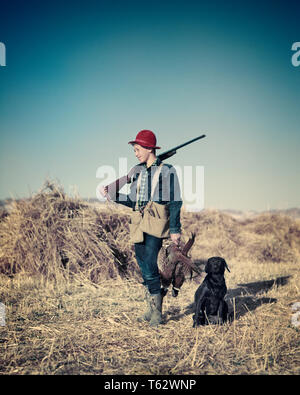 Anni Cinquanta ragazzo adolescente HUNTER NEL CAMPO CON IL CANE tenendo un tutore di fagiano con fucile sopra la sua spalla - kg239 HAR001 HARS UCCELLI DELLO STILE DI VITA RURALE spazio copia a tutta lunghezza persone maschi ragazzo adolescente HUNTER fiducia libertà successo fagiano mammiferi avventura il suo tempo libero canini caduta stagione orgoglio POOCH adolescente fagiani CANINE ARMA ARMI DA FUOCO novellame mammifero autunnale di rinforzo di etnia caucasica HAR001 in vecchio stile Foto Stock