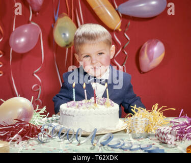 Anni sessanta sorridente ragazzo biondo indossare tuta blu ed il filtro Bow Tie guardando la telecamera pronta a soffiare le candeline sulla festa di compleanno torta - kj3950 HAR001 HARS STREAMERS STUDIO SHOT SALUBRITÀ HOME VITA amicizia a mezza lunghezza cura le espressioni di fiducia il contatto visivo indossare giacca e cravatta la felicità di testa e spalle allegro forza ed entusiasmo la ricreazione al sorriso gioioso concettuale supporto elegante soffiare il filtro Bow Tie crescita etnia caucasica HAR001 in vecchio stile Foto Stock