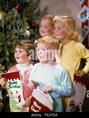 Anni sessanta ritratto 4 figli fratelli e sorelle sorridente DA ALBERO DI NATALE tenendo le calze indossando pigiami - kx3899 HAR001 HARS FEMMINE FRATELLI STUDIO SHOT SALUBRITÀ HOME VITA spazio copia amicizia a mezza lunghezza maschi pigiami fratelli sorelle BRUNETTE felicità allegro allegro ed entusiasmo i gemelli sorrisi connessione dicembre dicembre 25 F amichevole collaborazione gioiosa crescita JUVENILES gioiosa appartenenza etnica caucasica la vigilia di Natale HAR001 in vecchio stile Foto Stock