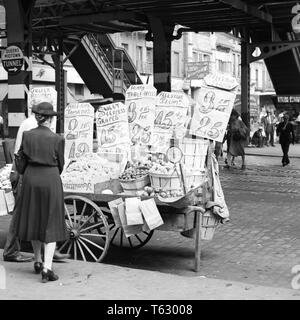 1930s 1940s 59TH STREET la terza Avenue sotto stazione EL donna shopping per le verdure al venditore ambulante spingere il carrello NEW YORK CITY USA - Q47436 CPC001 HARS B&W CLIENTE FORNITORE SCELTA DEL SERVIZIO ESTERNO A opportunità occupazioni di NYC CONCEPTUAL NEW YORK CITTÀ CONSUMATORE NEW YORK CITY SPINGERE IL CARRELLO COMMERCE FRUTTI MID-adulto metà donna adulta la terza Avenue 59TH STREET IN BIANCO E NERO di etnia caucasica in vecchio stile Foto Stock