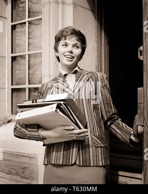 Anni Cinquanta anni sessanta sorridente COED passeggiate fuori porta il trasporto di libri notebook indossando giacca a strisce - S8304 HAR001 HARS spazio copia di metà lunghezza LADIES PERSONE FIDUCIA B&W BRUNETTE felicità allegro notebook stili di orgoglio sorride gioiosa elegante COED moda giovane donna adulta in bianco e nero di etnia caucasica HAR001 in vecchio stile Foto Stock