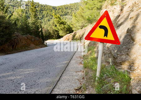 Segnale di avvertimento per il pericoloso girare a sinistra in montagna Foto Stock