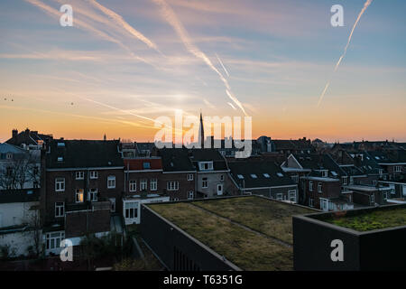 Incandescente tramonto multicolore a Maastricht. Contrails rilassante e nubi in un bellissimo cielo Foto Stock