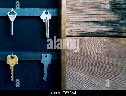 Chiavi appeso sul Golden ganci in una parete titolare di chiave sul legno rustico sfondo. Ipoteca, assicurazione, il concetto di sicurezza. Foto Stock