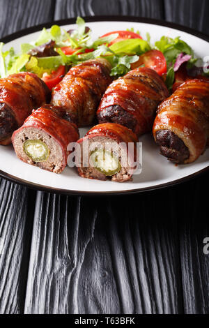 Fumato Armadillo uova con jalapeno e formaggio avvolto in pancetta servito con insalata fresca close-up su una piastra sul piano verticale. Foto Stock