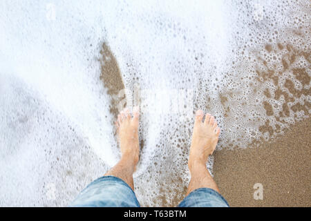 L'uomo i piedi sulla sabbia sulla costa. Foto Stock