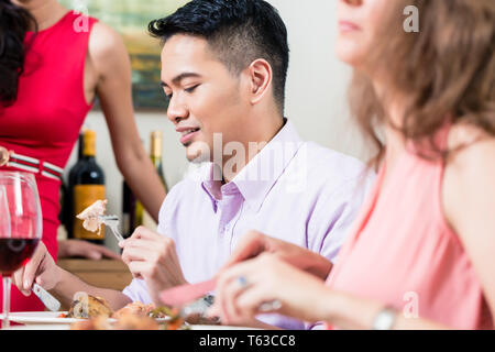 L'uomo mangiare con gli amici Foto Stock