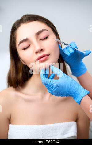 Estetista medico con tossina botulinica siringa rendendo iniezione per rimuovere Crow's piedi. Guancia volume migliorano la mesoterapia. Trattamento anti-aging e f Foto Stock