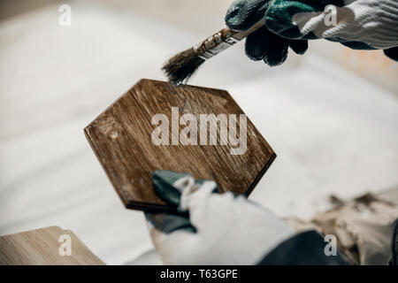 Lavoratore dipinge un prodotto di legno marrone. Primo piano Foto Stock