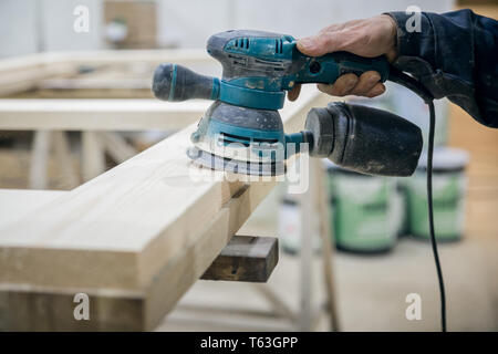Lavoratore levigatura della superficie in legno. Nel lato dell'utensile di potenza Foto Stock