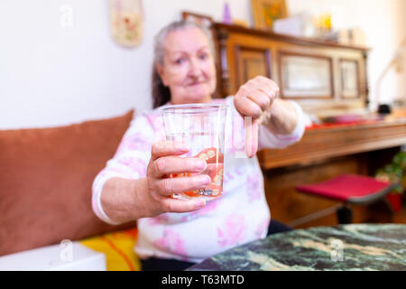 Protesi di una vecchia signora in un bicchiere di acqua Foto Stock