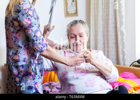 Una giovane donna dà un bicchiere di acqua ad una vecchia donna Foto Stock