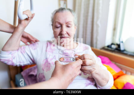 Una giovane donna dà un bicchiere di acqua ad una vecchia donna Foto Stock