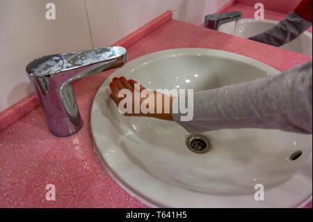 I bambini la mano sotto il rubinetto dal miscelatore in bagno di close-up. Foto Stock