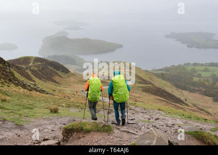 West Highland Way gli escursionisti a piedi verso il Loch Lomond e scendendo dalla collina conica in condizioni di tempo piovoso, Scotland, Regno Unito Foto Stock