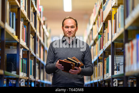 Oldenburg (Germania). Xi Apr, 2019. Stefan Walter, assegnista di ricerca presso l'Istituto di pedagogia presso il Carl von Ossietzky University Oldenburg, sorge in una libreria con pochi album di poesia nelle sue mani. Walter ha studiato e scritto la sua dissertazione sulla poesia album. Credito: Mohssen Assanimoghaddam/dpa/Alamy Live News Foto Stock