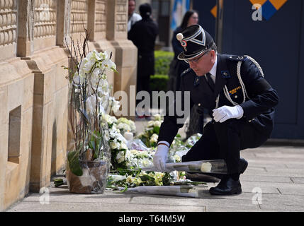 Luxemburg, Lussemburgo. 29 apr, 2019. Un poliziotto stabilisce una rosa bianca di fronte al Palazzo del Granduca del Lussemburgo per l'addio a Lussemburgo l'ex Granduca Jean. Il corpo è stato stabilito per cinque giorni nel Grand Ducal Palace nella capitale. Credito: Harald Tittel/dpa/Alamy Live News Foto Stock