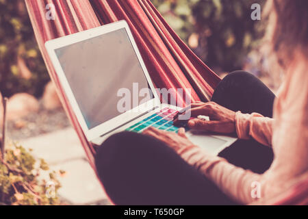 Il nomade digitale e lavorare ovunque con la tecnologia internet e computer laptop - donna adulta mani la digitazione su keayboard in colorati filtro vintage Foto Stock