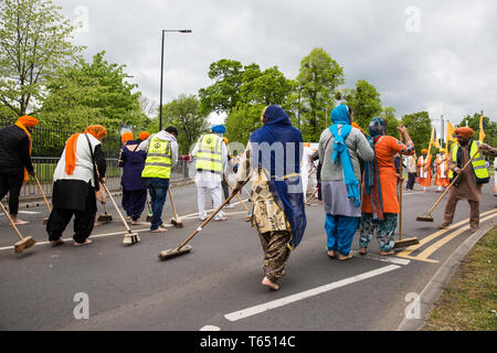 Slough, Regno Unito. Il 28 aprile 2019. La religione sikh donne noto come 'sewadars' spazzare il percorso del Vaisakhi Nagar Kirtan processione. Vaisakhi è il santissimo giorno in Foto Stock