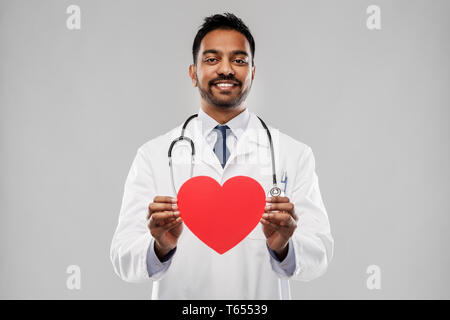 Sorridente maschio indiano medico con cuore rosso forma Foto Stock