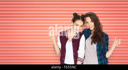 Felice ragazze adolescenti o amici mostrando pollice in alto Foto Stock