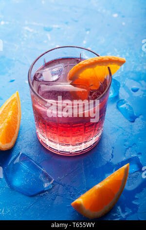 Fresh ice tea summer cocktail con arancia e ghiaccio in vetro su sfondo blu, orientamento verticale Foto Stock
