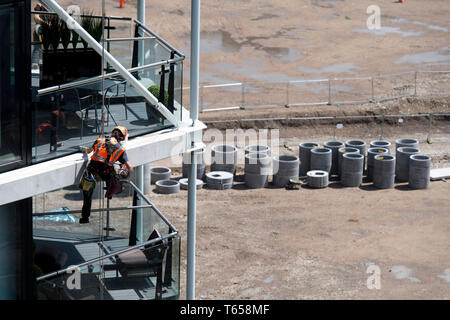 Un lavoratore edile abseils fino al 8 piano di Riverlight Quay Appartamento Edificio per praticare un foro. Nine Elms nel sud di Londra su 12/07/2017 Foto Stock